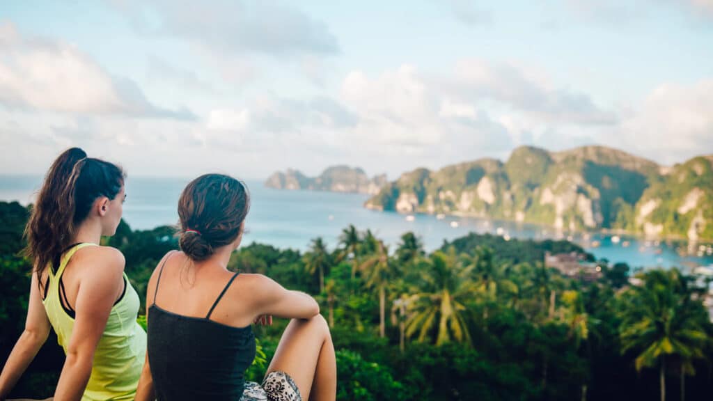 two women sitting on cliff in thailand