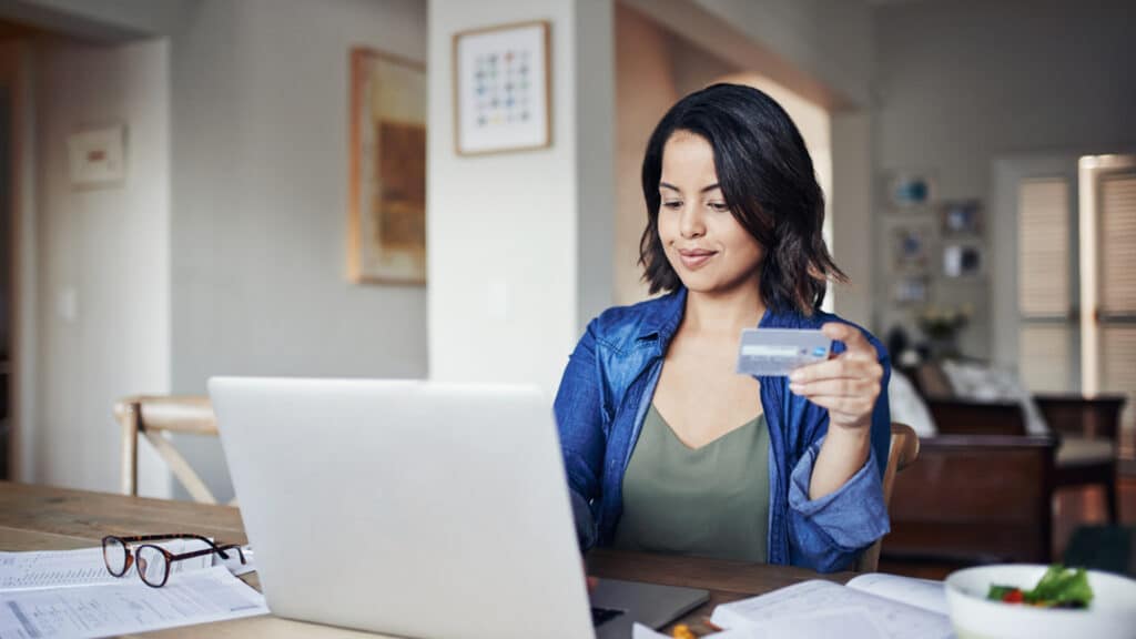 woman paying bills online holding credit card