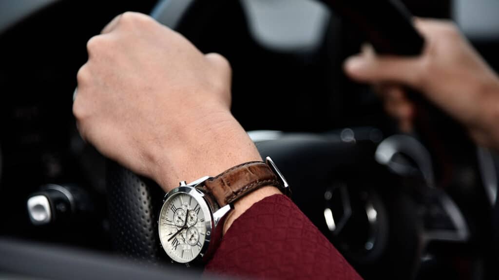 nice watch on hand in nice car