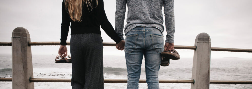 couple holding hands on boardwalk