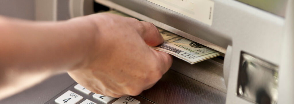 person taking cash out of atm