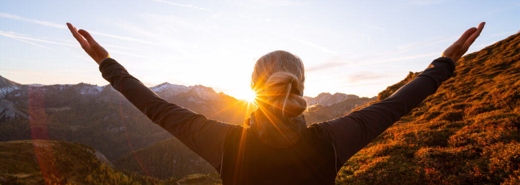 woman with arms up in the mountain